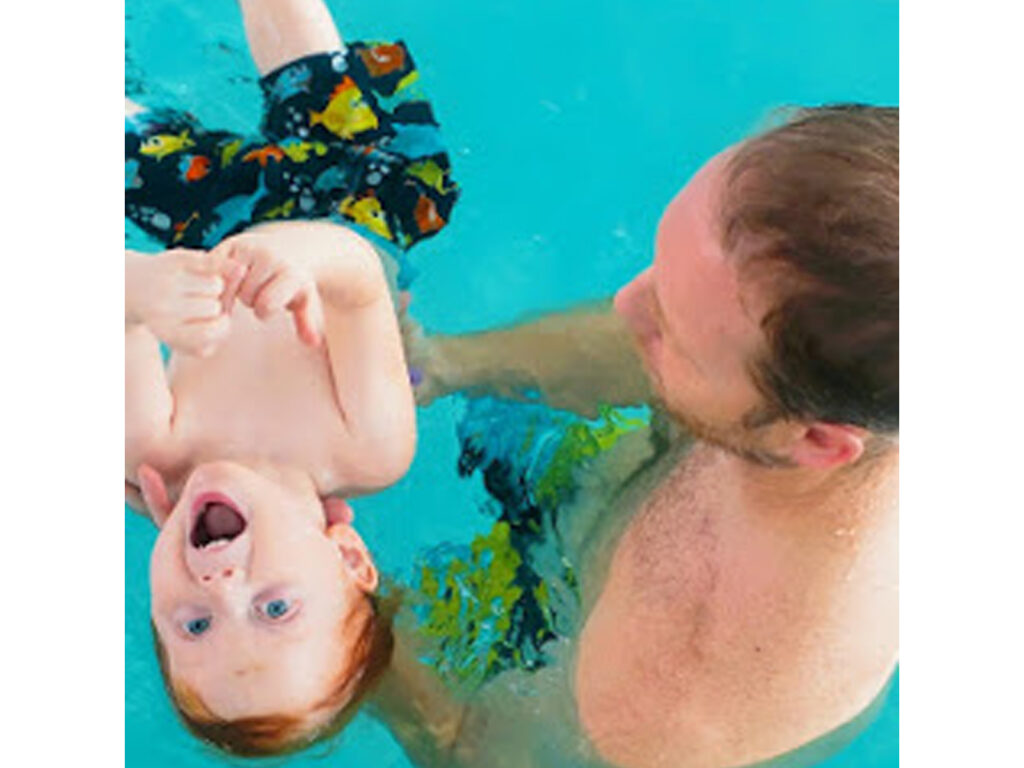 A man and his son swimming in the pool.