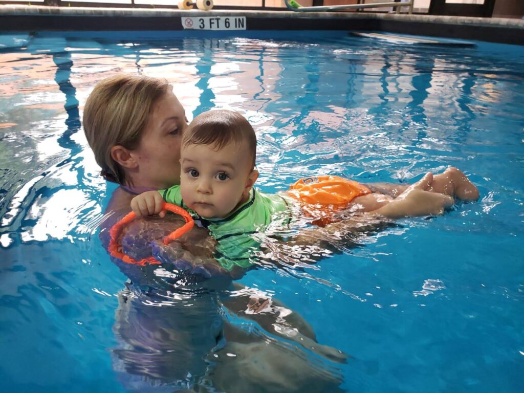 A woman and child in the water with a toy.