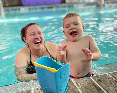 A woman and child in the pool playing with a toy.