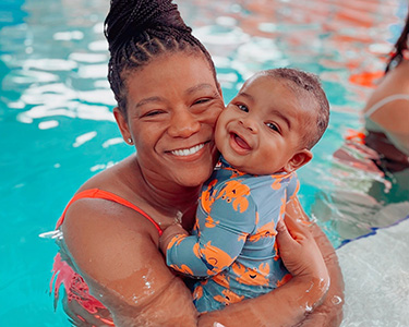 A woman holding a baby in the pool