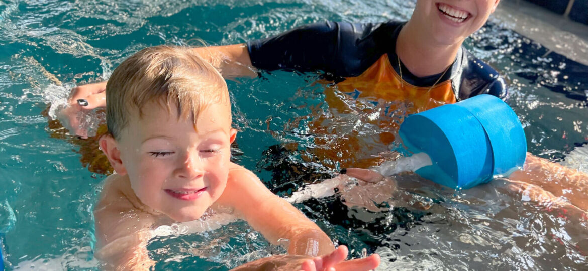 A boy and girl in the pool playing with water toys.